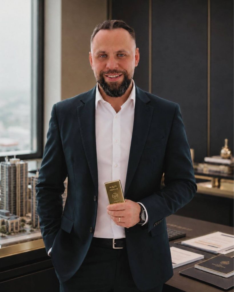 Artur Runge, Finanzberater für Immobilien und Edelmetalle, mit Goldbarren in einem eleganten Büro